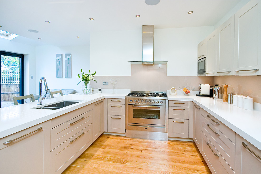 Foto på ett mellanstort funkis kök och matrum, med en integrerad diskho, grå skåp, marmorbänkskiva, beige stänkskydd, rostfria vitvaror och mellanmörkt trägolv