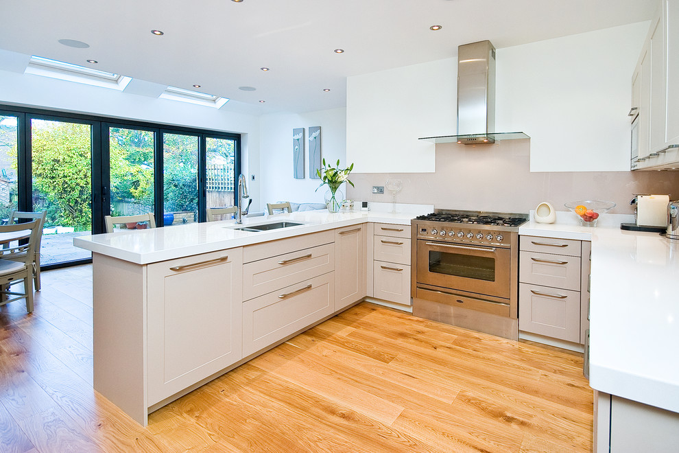 Photo of a medium sized modern kitchen/diner in London with an integrated sink, grey cabinets, marble worktops, beige splashback, stainless steel appliances and medium hardwood flooring.