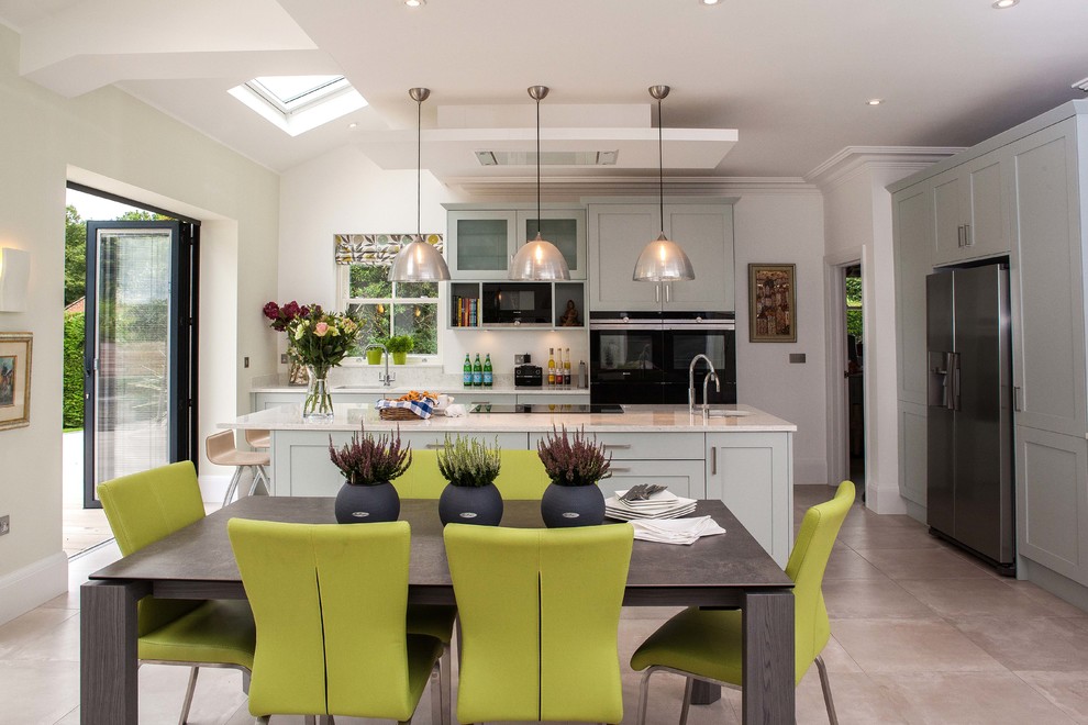 Inspiration for a large contemporary l-shaped kitchen/diner in Surrey with a double-bowl sink, shaker cabinets, blue cabinets, quartz worktops, black appliances, limestone flooring, an island and grey floors.