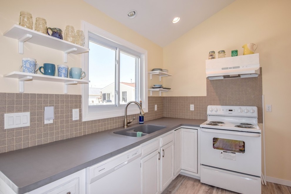 Foto di una cucina costiera di medie dimensioni con lavello sottopiano, ante con finitura invecchiata, top in superficie solida, paraspruzzi con piastrelle in pietra e pavimento grigio