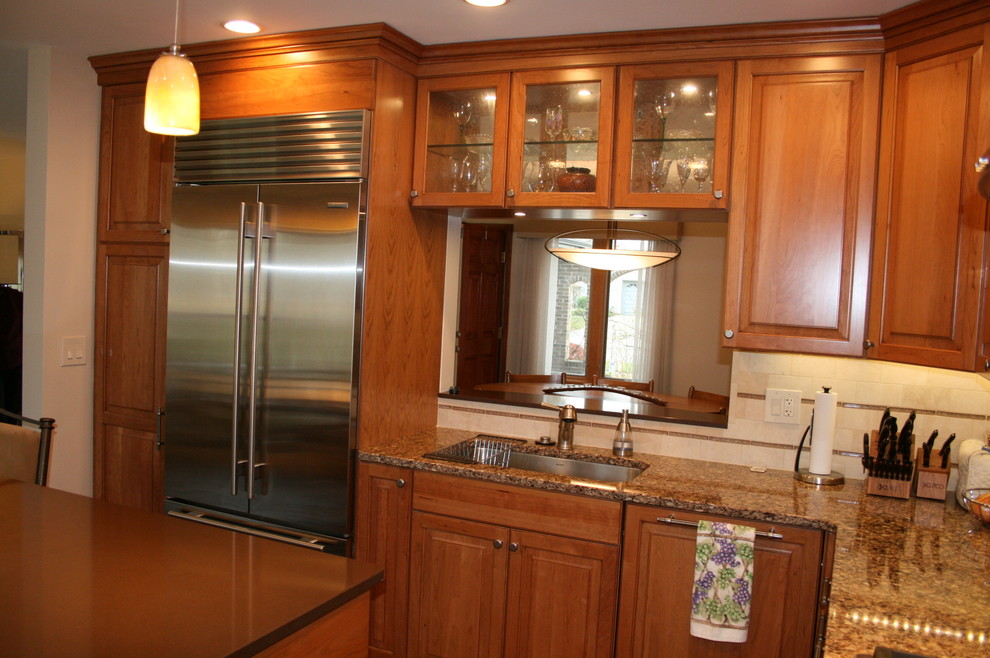 Example of a mid-sized transitional l-shaped dark wood floor enclosed kitchen design in Chicago with an undermount sink, raised-panel cabinets, medium tone wood cabinets, quartz countertops, beige backsplash, stone tile backsplash, stainless steel appliances and an island