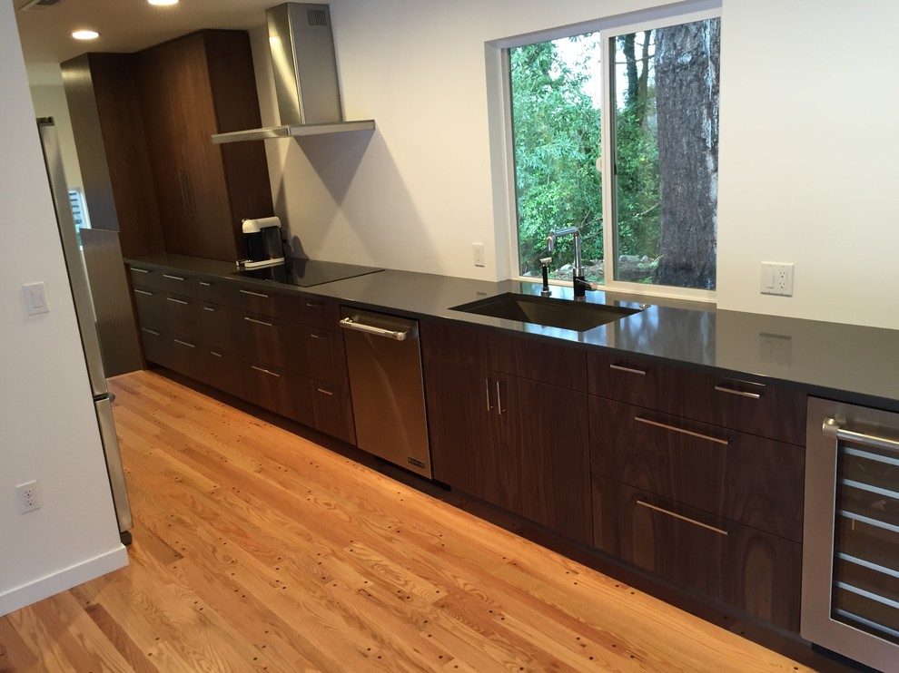 Inspiration for a mid-century modern galley medium tone wood floor eat-in kitchen remodel in Portland with flat-panel cabinets, dark wood cabinets, stainless steel appliances, no island, an undermount sink and quartz countertops