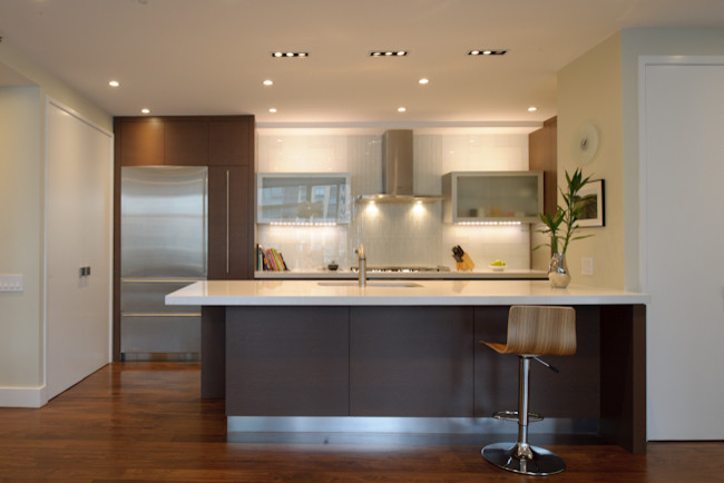 Foto de cocina moderna sin isla con armarios con paneles lisos, puertas de armario de madera oscura, salpicadero azul y electrodomésticos de acero inoxidable