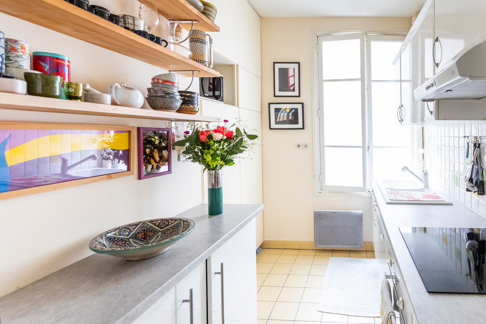 Inspiration for a small modern galley enclosed kitchen in Paris with flat-panel cabinets, white cabinets, laminate countertops, white splashback, ceramic splashback, integrated appliances, ceramic flooring, no island, white floors and grey worktops.