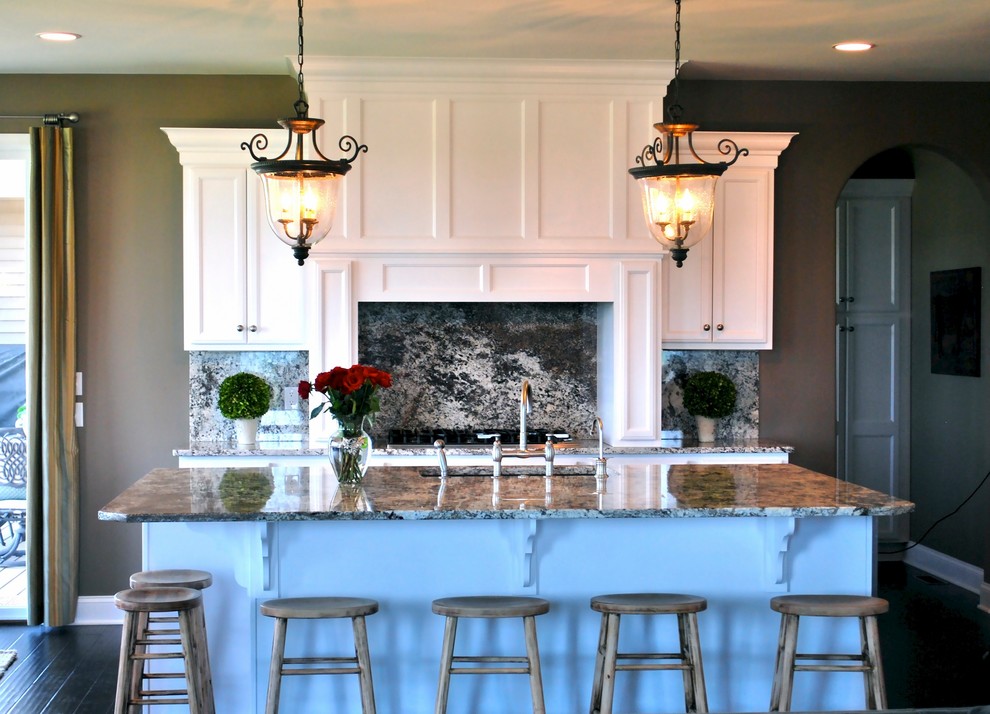 Foto di un cucina con isola centrale classico con lavello sottopiano, ante con riquadro incassato, ante bianche, top in granito e parquet scuro