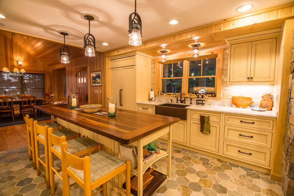 Idéer för avskilda, mellanstora rustika kök, med en rustik diskho, luckor med profilerade fronter, skåp i slitet trä, marmorbänkskiva, vitt stänkskydd, stänkskydd i travertin, integrerade vitvaror, skiffergolv, en köksö och flerfärgat golv