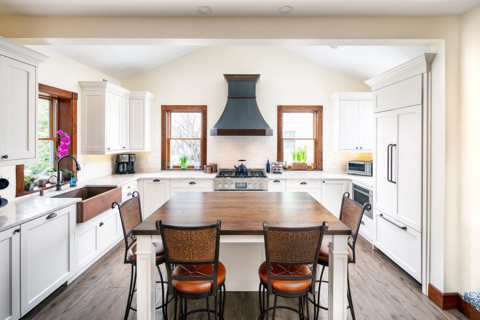 Kitchen - transitional u-shaped brown floor kitchen idea in Newark with a farmhouse sink, shaker cabinets, white cabinets, white backsplash, paneled appliances, an island and white countertops