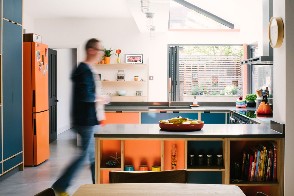 Идея дизайна: п-образная кухня в скандинавском стиле с обеденным столом, одинарной мойкой, плоскими фасадами, оранжевыми фасадами, цветной техникой, бетонным полом, полуостровом, серым полом и серой столешницей