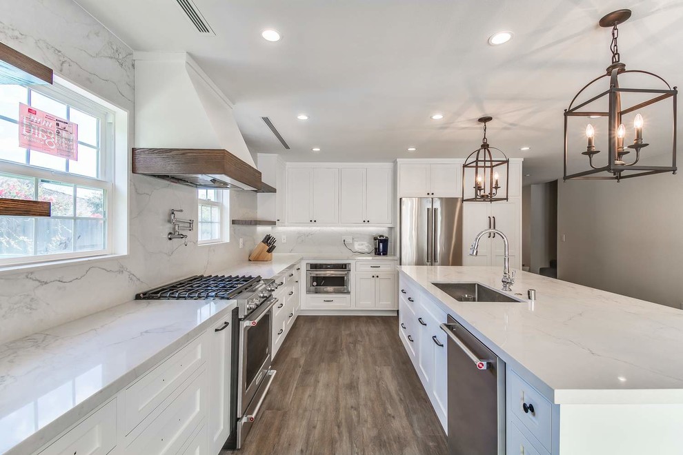 Mid-sized trendy u-shaped porcelain tile and brown floor eat-in kitchen photo in Orange County with an undermount sink, recessed-panel cabinets, white cabinets, quartz countertops, white backsplash, stone slab backsplash, stainless steel appliances, an island and white countertops