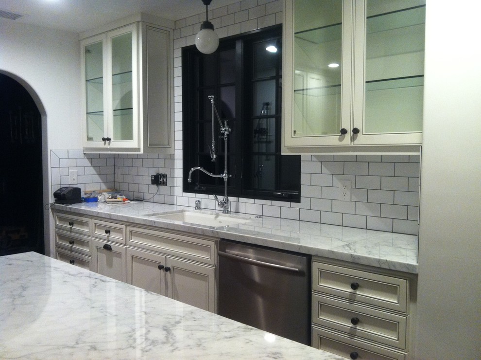 Bild på ett stort funkis kök, med en undermonterad diskho, skåp i shakerstil, grå skåp, marmorbänkskiva, vitt stänkskydd, stänkskydd i porslinskakel, rostfria vitvaror, mörkt trägolv och en köksö
