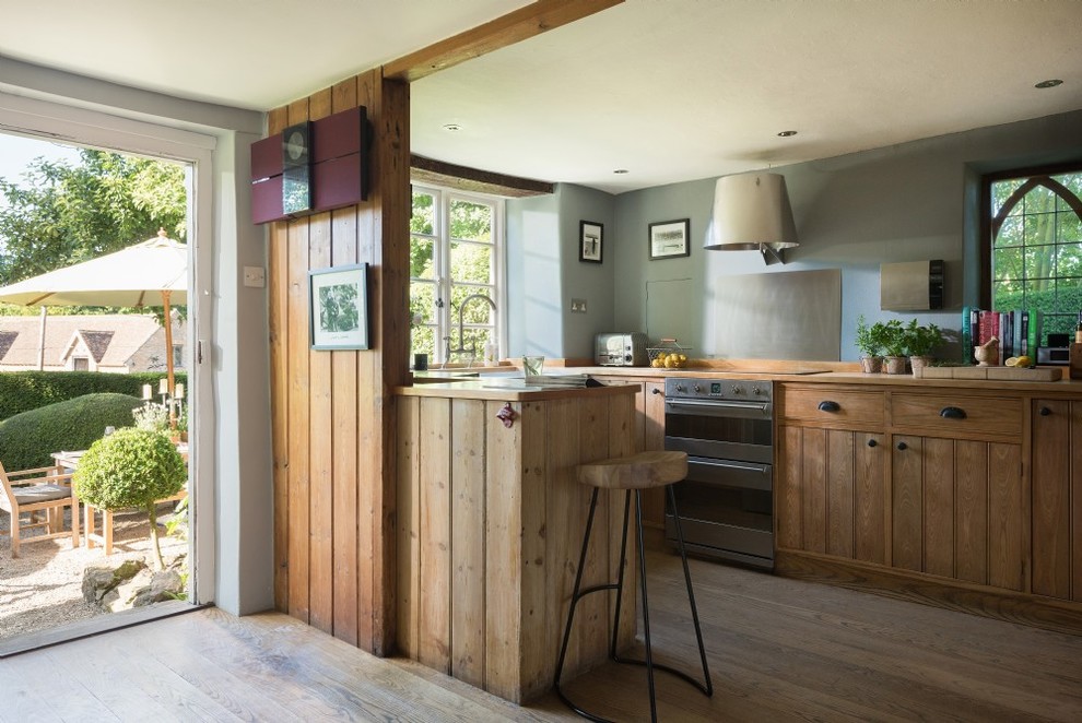 Landhaus Küche in U-Form mit hellbraunen Holzschränken, Küchenrückwand in Metallic, braunem Holzboden, Halbinsel, braunem Boden und flächenbündigen Schrankfronten in Dorset