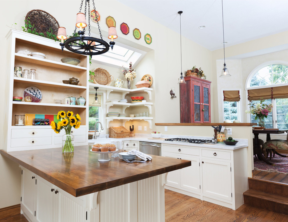 Mid-sized farmhouse u-shaped medium tone wood floor eat-in kitchen photo in Minneapolis with a farmhouse sink, beaded inset cabinets, white cabinets, wood countertops, beige backsplash, stainless steel appliances and an island