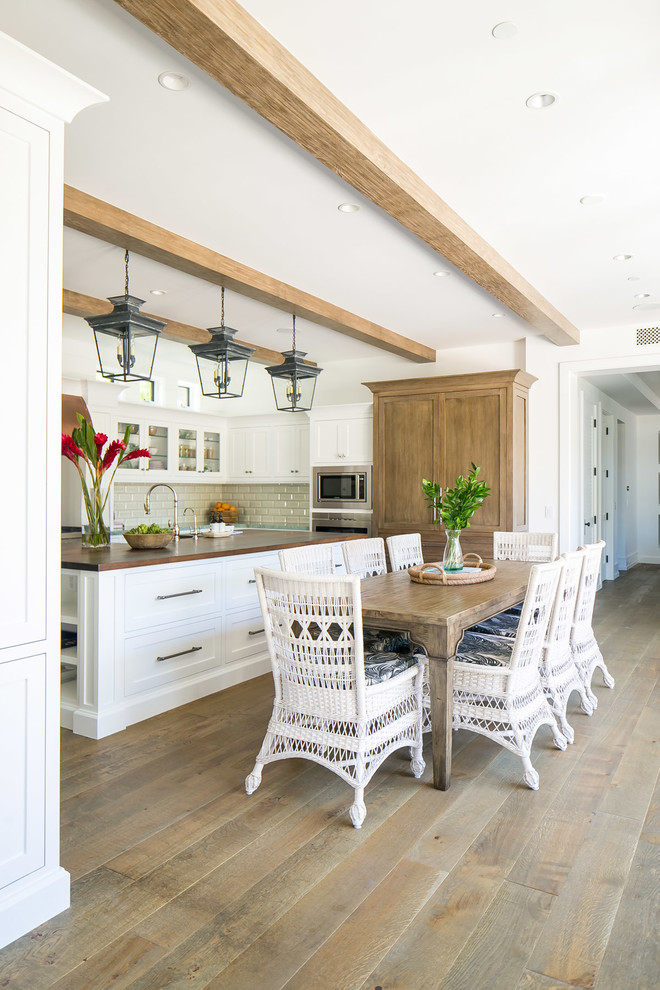 Eat-in kitchen - large tropical u-shaped medium tone wood floor and brown floor eat-in kitchen idea in Orange County with a double-bowl sink, shaker cabinets, white cabinets, wood countertops, white backsplash, subway tile backsplash, stainless steel appliances, an island and brown countertops