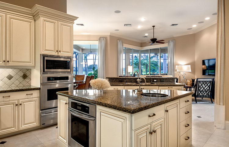 Inspiration for a traditional kitchen in Tampa with a submerged sink, raised-panel cabinets, white cabinets, granite worktops, beige splashback, porcelain flooring and multiple islands.