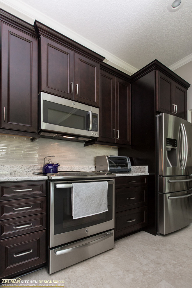 Mittelgroße Klassische Wohnküche in L-Form mit Unterbauwaschbecken, Schrankfronten mit vertiefter Füllung, dunklen Holzschränken, Granit-Arbeitsplatte, Porzellan-Bodenfliesen und Kücheninsel in Orlando