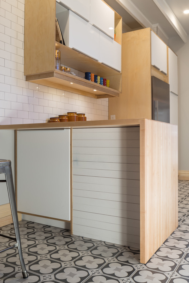 Inspiration for a small contemporary ceramic tile enclosed kitchen remodel in Ottawa with a farmhouse sink, flat-panel cabinets, white cabinets, wood countertops, white backsplash, subway tile backsplash, stainless steel appliances and a peninsula