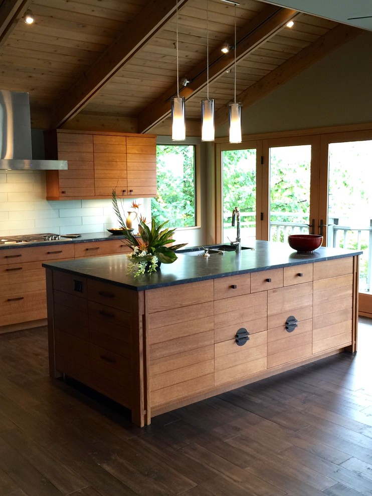 This is an example of a medium sized modern l-shaped kitchen/diner in Seattle with a submerged sink, flat-panel cabinets, medium wood cabinets, soapstone worktops, glass tiled splashback, stainless steel appliances, dark hardwood flooring and an island.
