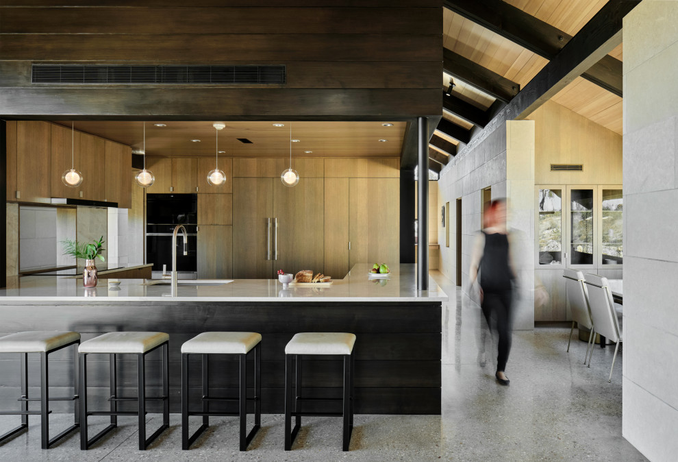 Foto di una cucina contemporanea di medie dimensioni con lavello sottopiano, ante lisce, ante in legno scuro, elettrodomestici da incasso, pavimento in cemento, pavimento grigio, top bianco e soffitto in legno