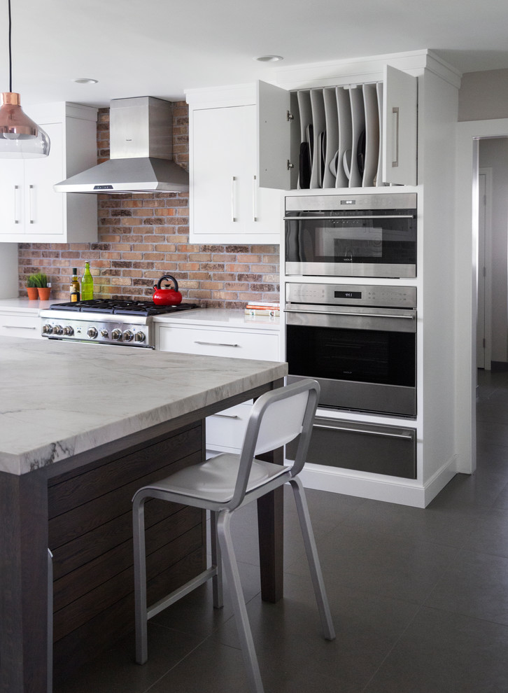 Mid-sized transitional l-shaped porcelain tile and gray floor eat-in kitchen photo in New York with a single-bowl sink, flat-panel cabinets, white cabinets, quartzite countertops, brown backsplash, brick backsplash, stainless steel appliances and an island