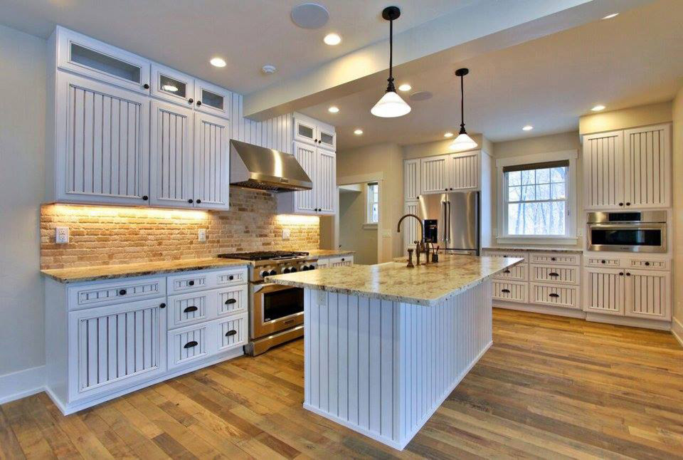 Foto på ett mellanstort funkis kök, med en enkel diskho, luckor med upphöjd panel, vita skåp, marmorbänkskiva, svarta vitvaror, mellanmörkt trägolv och en köksö