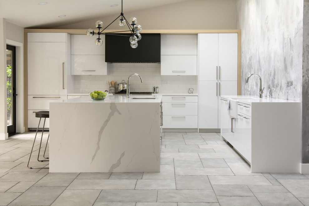 Eat-in kitchen - large modern l-shaped limestone floor and gray floor eat-in kitchen idea in San Francisco with a farmhouse sink, flat-panel cabinets, white cabinets, quartz countertops, white backsplash, subway tile backsplash, paneled appliances, an island and white countertops