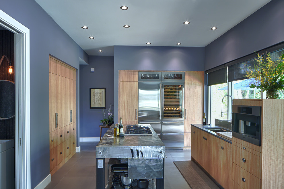 Diseño de cocina contemporánea con armarios con paneles lisos, puertas de armario de madera clara y electrodomésticos de acero inoxidable