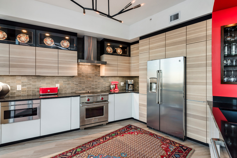 Mid-sized trendy u-shaped light wood floor and beige floor open concept kitchen photo in Orlando with flat-panel cabinets, light wood cabinets, beige backsplash, stainless steel appliances, no island, black countertops, quartz countertops and ceramic backsplash