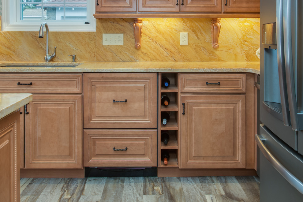 Klassisk inredning av ett avskilt, stort l-kök, med en undermonterad diskho, luckor med upphöjd panel, skåp i mellenmörkt trä, granitbänkskiva, gult stänkskydd, stänkskydd i sten, rostfria vitvaror, en köksö, ljust trägolv och brunt golv