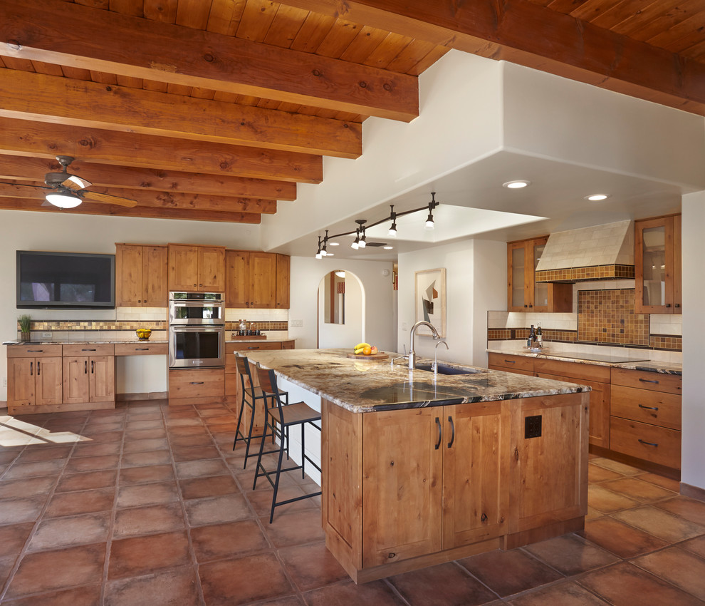 Idéer för att renovera ett mycket stort amerikanskt brun brunt kök, med en undermonterad diskho, luckor med infälld panel, skåp i ljust trä, granitbänkskiva, brunt stänkskydd, stänkskydd i glaskakel, rostfria vitvaror, klinkergolv i terrakotta, en köksö och brunt golv
