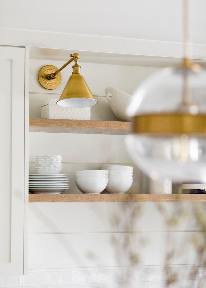 Bild på ett vintage vit vitt kök, med en undermonterad diskho, skåp i shakerstil, vita skåp, bänkskiva i kvarts, vitt stänkskydd, stänkskydd i tunnelbanekakel, rostfria vitvaror, klinkergolv i keramik och en köksö