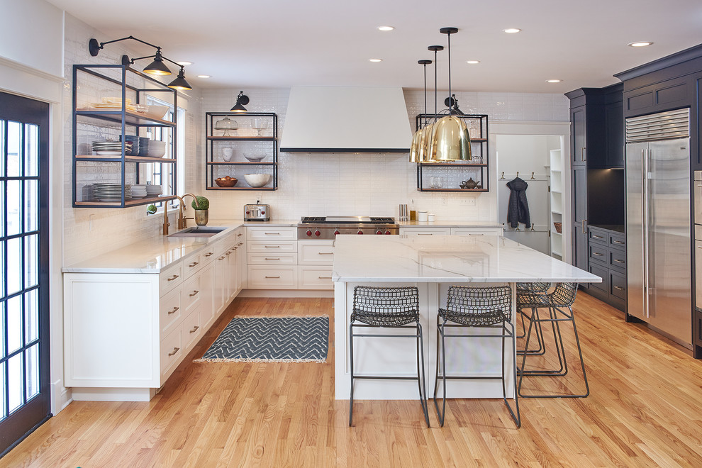 Example of a large transitional l-shaped light wood floor kitchen design in Minneapolis with an undermount sink, white cabinets, quartzite countertops, white backsplash, subway tile backsplash, stainless steel appliances, an island, white countertops and recessed-panel cabinets