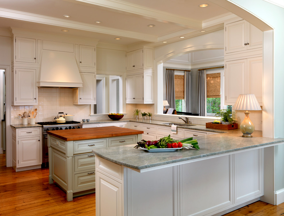 Example of a large classic u-shaped medium tone wood floor eat-in kitchen design in Jacksonville with an undermount sink, beaded inset cabinets, white cabinets, marble countertops, white backsplash, cement tile backsplash, paneled appliances and an island