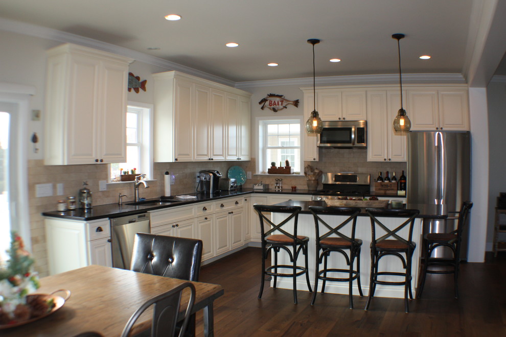 Exempel på ett mellanstort shabby chic-inspirerat kök, med en undermonterad diskho, luckor med upphöjd panel, vita skåp, bänkskiva i kvartsit, beige stänkskydd, stänkskydd i stenkakel, rostfria vitvaror, mellanmörkt trägolv och en köksö