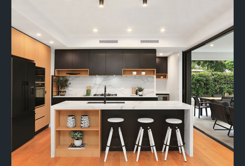 Inspiration for a large contemporary l-shaped beige floor kitchen remodel in Brisbane with an undermount sink, flat-panel cabinets, black cabinets, white backsplash, black appliances, an island and white countertops