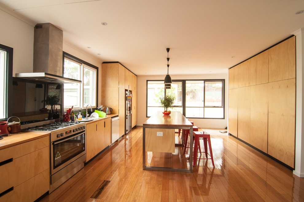 Photo of a large contemporary galley kitchen in Melbourne with a built-in sink, flat-panel cabinets, medium wood cabinets, wood worktops, black splashback, stainless steel appliances, medium hardwood flooring and an island.