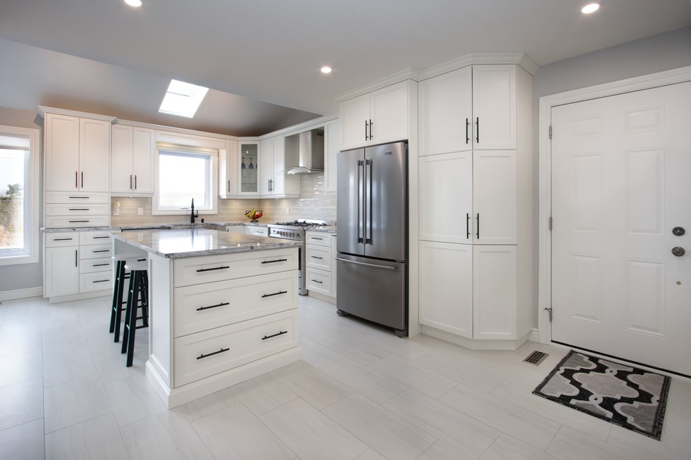 Inspiration for a medium sized classic l-shaped kitchen/diner in Toronto with a belfast sink, shaker cabinets, white cabinets, engineered stone countertops, white splashback, mosaic tiled splashback, stainless steel appliances, porcelain flooring, an island, grey floors and grey worktops.