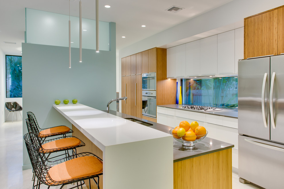 Zweizeilige Moderne Küche mit Doppelwaschbecken, flächenbündigen Schrankfronten, hellbraunen Holzschränken, Küchengeräten aus Edelstahl und Kücheninsel in Tampa