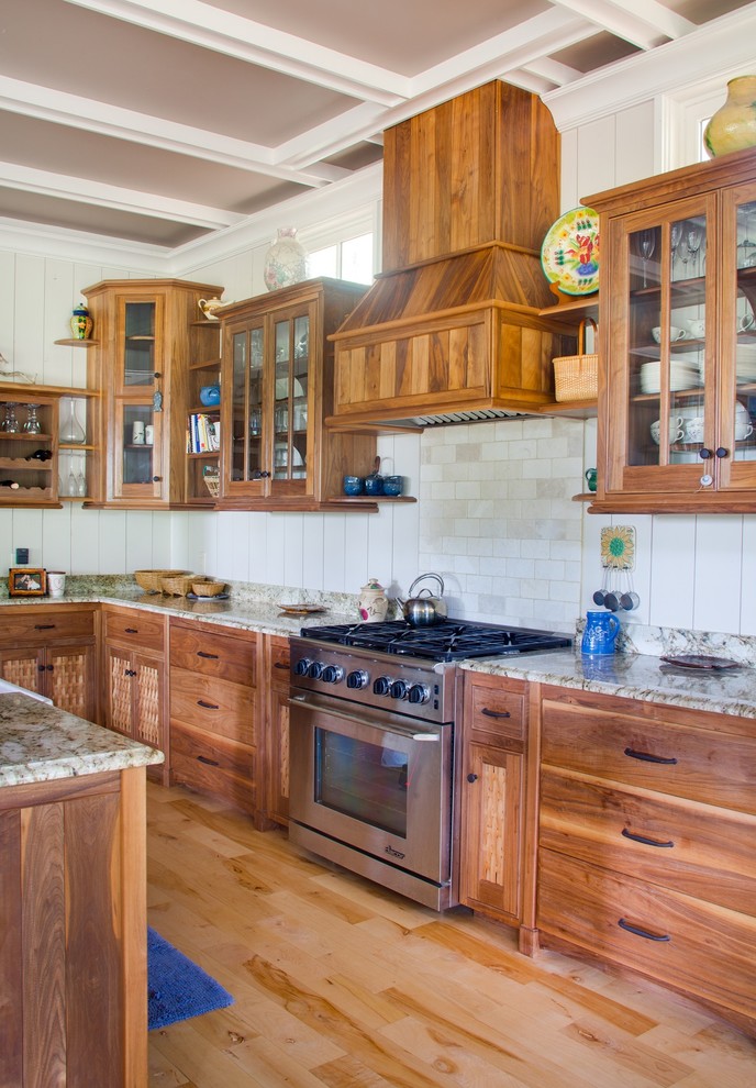Bild på ett vintage l-kök, med skåp i shakerstil, skåp i mellenmörkt trä, vitt stänkskydd, stänkskydd i tunnelbanekakel, rostfria vitvaror, ljust trägolv och en köksö