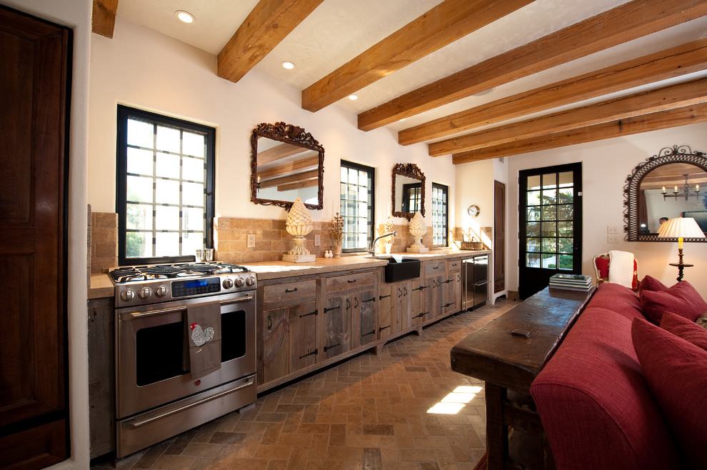 Inredning av ett rustikt mellanstort kök, med rostfria vitvaror, en rustik diskho, släta luckor, skåp i mellenmörkt trä, marmorbänkskiva, beige stänkskydd, stänkskydd i stenkakel och travertin golv