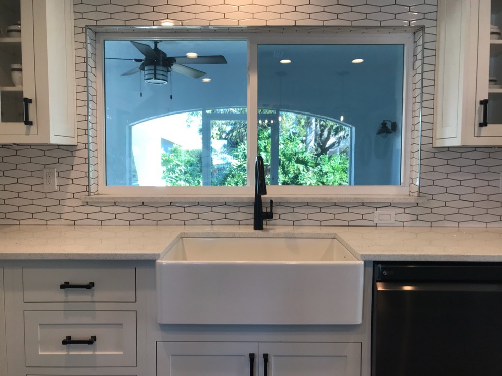 Bild på ett mellanstort retro vit vitt kök, med en rustik diskho, skåp i shakerstil, vita skåp, bänkskiva i kvarts, vitt stänkskydd, stänkskydd i porslinskakel, rostfria vitvaror, klinkergolv i porslin, en köksö och grått golv