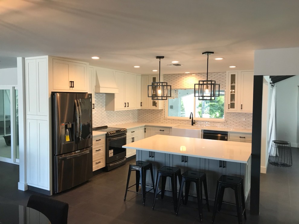 Medium sized retro l-shaped kitchen/diner in Tampa with a belfast sink, shaker cabinets, white cabinets, engineered stone countertops, white splashback, porcelain splashback, stainless steel appliances, porcelain flooring, an island, grey floors and white worktops.