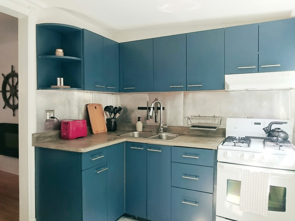 Inredning av ett nordiskt litet kök, med en dubbel diskho, släta luckor, blå skåp, bänkskiva i betong, stänkskydd med metallisk yta och vita vitvaror