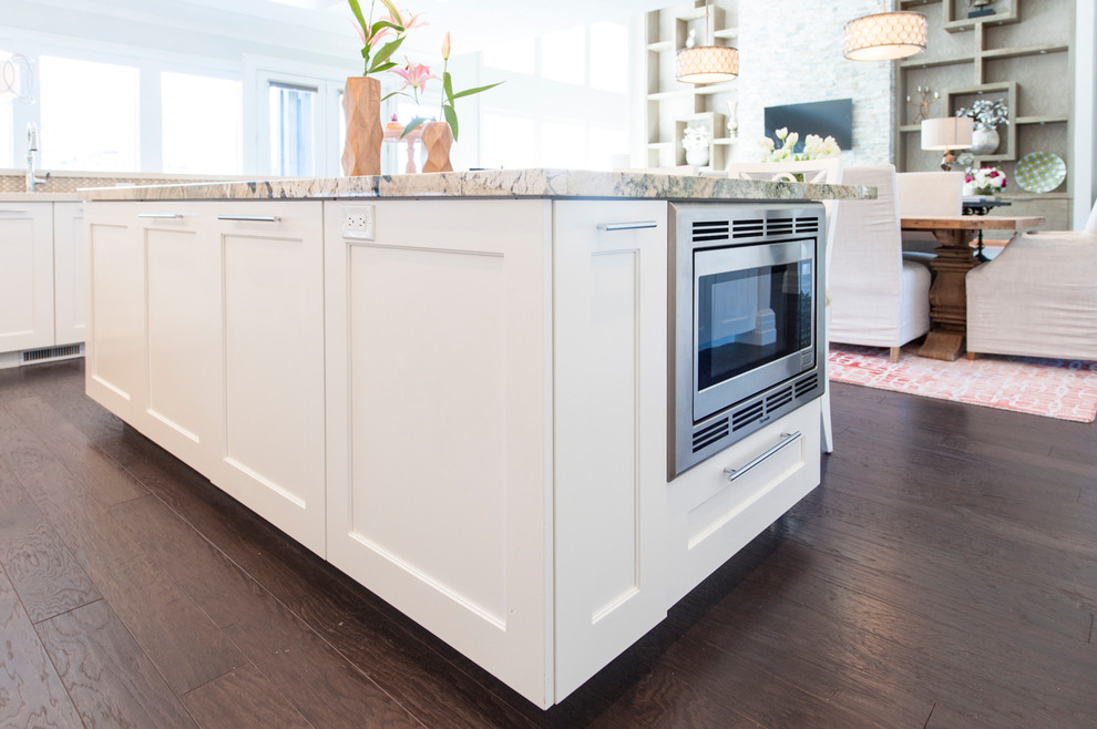 This is an example of a large scandinavian u-shaped kitchen/diner in Salt Lake City with shaker cabinets, white cabinets, an island, a submerged sink, granite worktops, white splashback, stainless steel appliances, dark hardwood flooring and black floors.