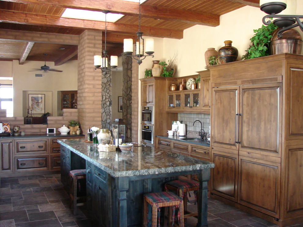 Foto på ett stort medelhavsstil kök, med en enkel diskho, luckor med infälld panel, skåp i mellenmörkt trä, marmorbänkskiva, beige stänkskydd, stänkskydd i stenkakel, skiffergolv, en köksö, svarta vitvaror och grått golv