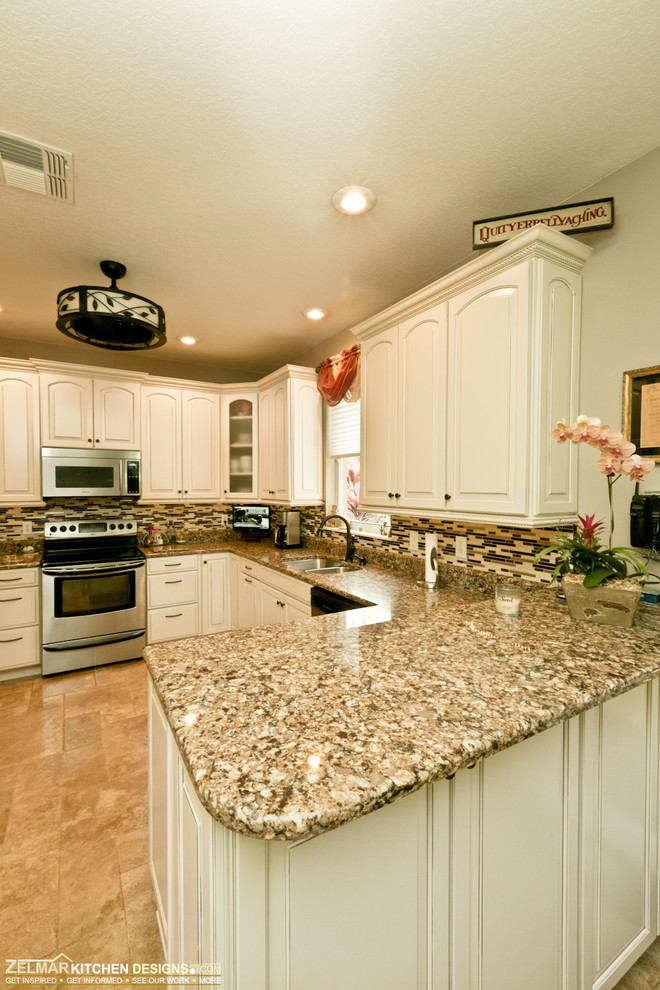Klassisk inredning av ett mellanstort kök, med luckor med upphöjd panel, vita skåp, bänkskiva i kvarts, flerfärgad stänkskydd, glaspanel som stänkskydd, travertin golv och en halv köksö