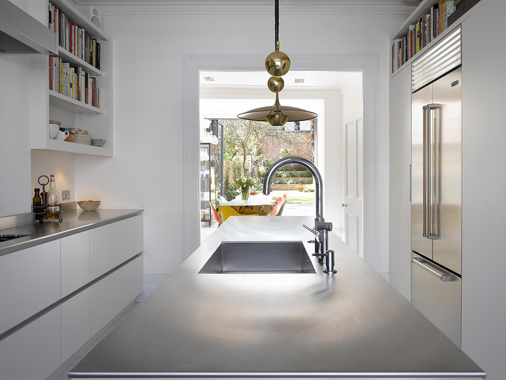 Bild på ett mellanstort funkis grå grått kök, med släta luckor, vita skåp, bänkskiva i rostfritt stål, grått stänkskydd, rostfria vitvaror, målat trägolv, en köksö och vitt golv