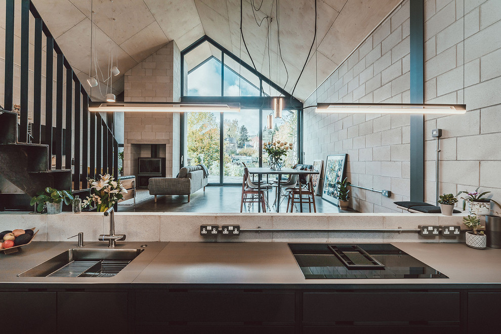 Inspiration for a mid-sized modern galley concrete floor and gray floor open concept kitchen remodel in Other with a drop-in sink, flat-panel cabinets, gray cabinets, stainless steel countertops, paneled appliances, no island and gray countertops