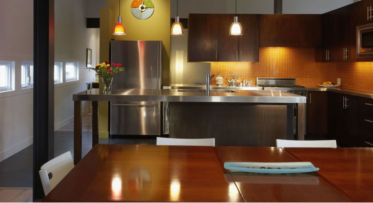 Immagine di una cucina contemporanea di medie dimensioni con ante lisce, ante in legno bruno, top in acciaio inossidabile, paraspruzzi arancione, paraspruzzi con piastrelle di vetro e elettrodomestici in acciaio inossidabile