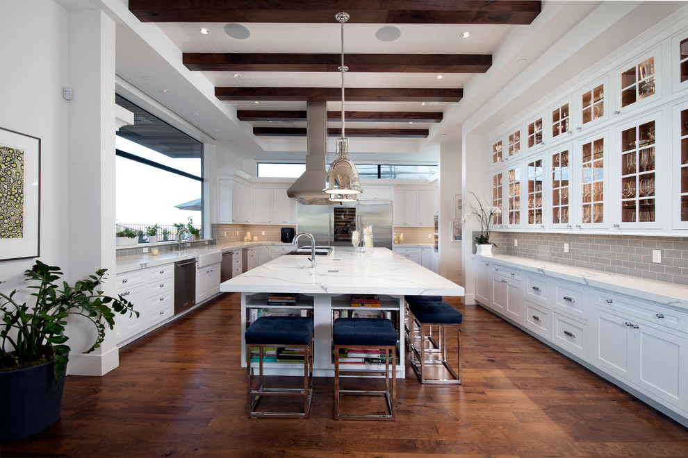 Enclosed kitchen - large modern u-shaped dark wood floor and brown floor enclosed kitchen idea in Las Vegas with a farmhouse sink, shaker cabinets, white cabinets, quartzite countertops, gray backsplash, subway tile backsplash, stainless steel appliances, an island and white countertops