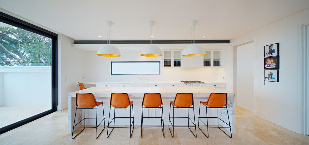 На фото: параллельная кухня среднего размера в современном стиле с обеденным столом, с полувстраиваемой мойкой (с передним бортиком), белыми фасадами, мраморной столешницей и островом